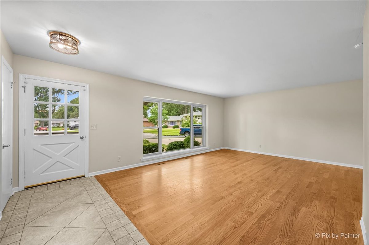 Living room with hardwood floors, a picture window, and the front entry