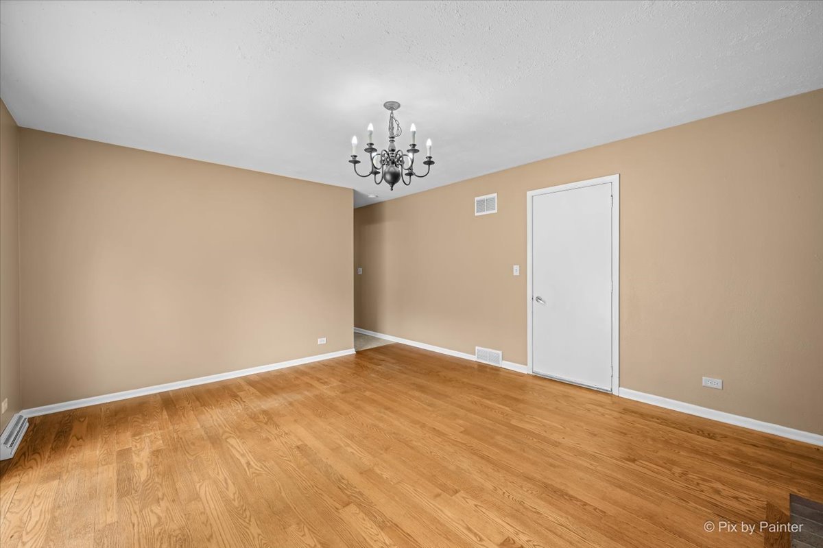 Empty bedroom with hardwood floors and a chandelier