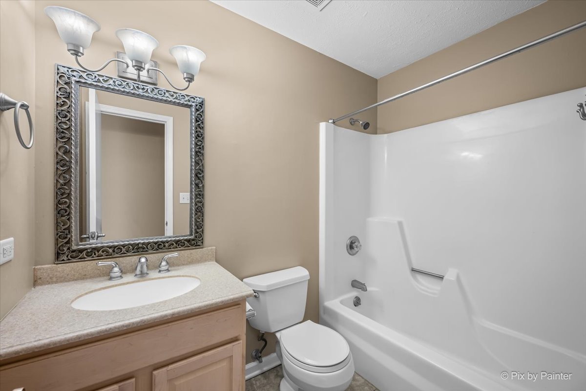 Full bathroom with a framed mirror, vanity, and tub-shower combination