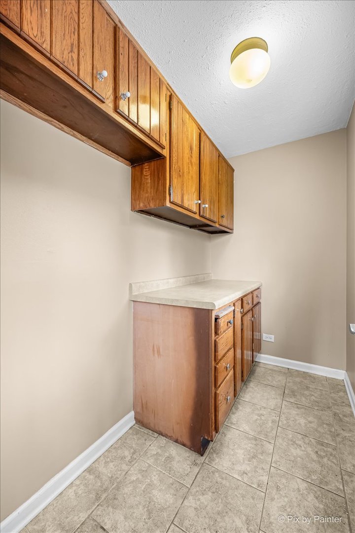 Utility room with original wood cabinets and tile flooring